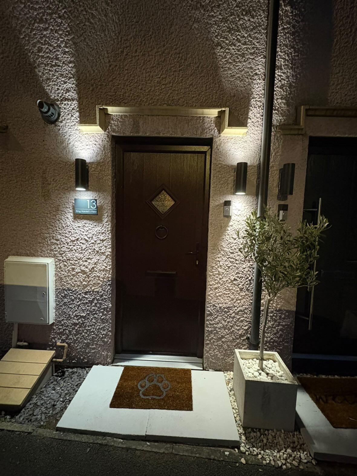 Modern outdoor cylinder wall lights flanking a front door for improved home security