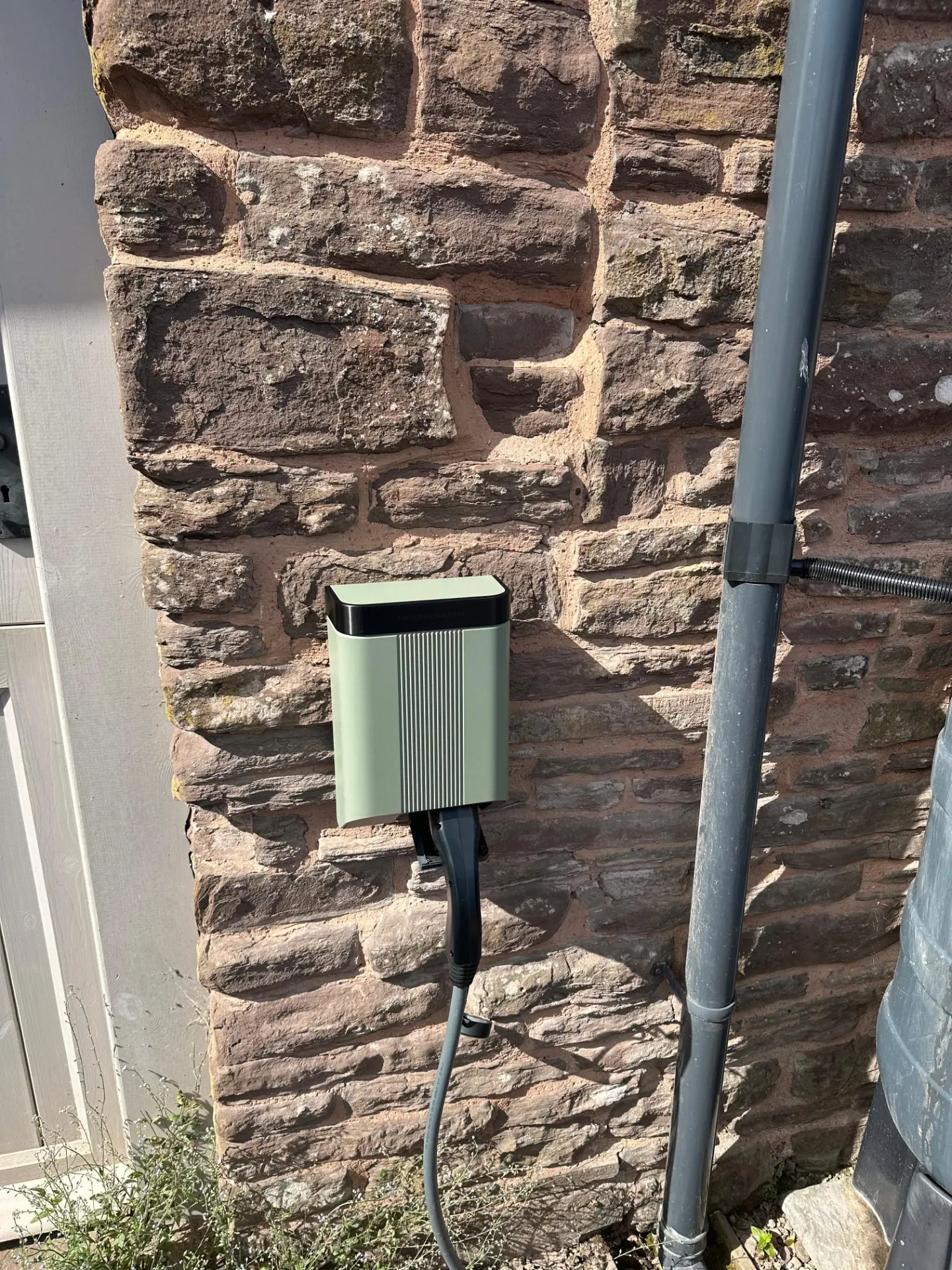 Sage green home EV charge point installed on a red sandstone wall by a NAPIT registered electrician